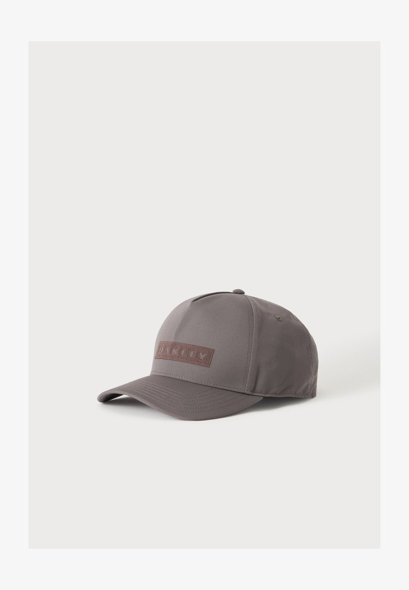 Casquette de baseball grise avec une visière incurvée et un patch rectangulaire cousu centré sur le panneau avant.