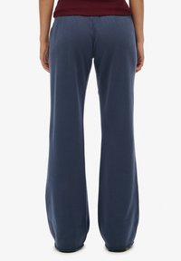 Granatowe spodnie dzwony z miękkiego materiału, charakteryzujące się gładką teksturą, elastycznym pasem i luźnym krojem do kostek.