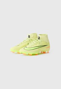 Scarpe da calcio verde lime con un design a profilo basso, caratterizzate da accenti neri, upper testurizzato e suole con borchie arancioni per una migliore aderenza.