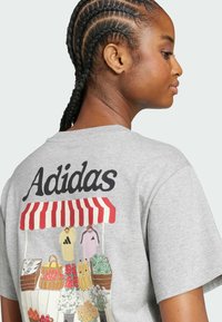 Grå bomullströja med en marknadsscen grafik på baksidan, med broderade frukter, blommor och Adidas-logotyp i fet stil.