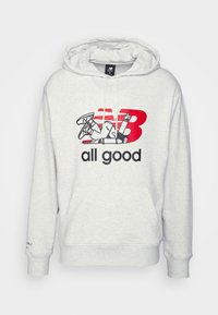 Hoodie grigio chiaro con tasca a canguro frontale e cappuccio con lacci. Presenta il logo New Balance rosso e nero e una grafica in stile cartone animato. Tessuto morbido.