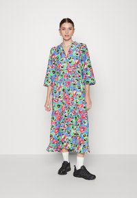 Vestido midi padronizado em azul, com um design floral com detalhes em vermelho e verde, mangas três quartos e uma bainha em camadas com voltas.