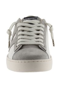 Sneaker bianco e grigio con materiali in suede e pelle, punta tonda, lacci piatti e suola testurizzata. Presenta un'etichetta con logo sulla linguetta.