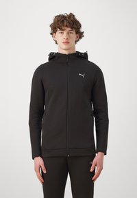 Felpa nera con zip, realizzata in tessuto liscio, con cappuccio, tasche laterali e un piccolo logo bianco sul lato sinistro del petto. Design aderente.