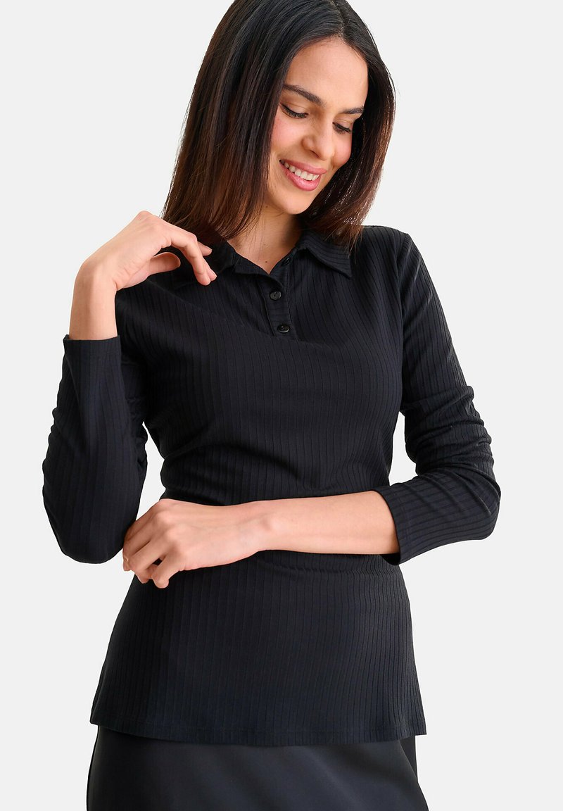 Zwarte geribbelde blouse met lange mouwen, een kraag, een drieknoopssluiting en een aangesloten silhouet, met een gladde textuur.