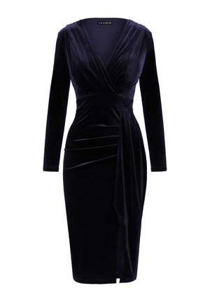Robe en velours bleu marine profond avec des manches longues, un col en V et un détail drapé à la taille. Présente une fente à l'avant pour un élément de design supplémentaire.