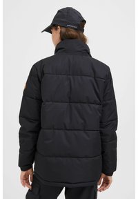 Svart pufferjakke med høy krage, quiltet design, elastiske mansjetter og en merket lapp på venstre skulder. Matt finish.
