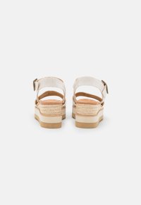Beige platform sandalen met gestructureerde geweven banden, verstelbare enkelband en een chunky lichtbruine zool met een zigzagpatroon.