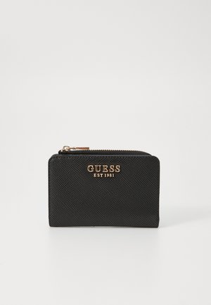 Portefeuille texturé noir avec le logo doré 'GUESS EST 1981'. Il dispose d'une fermeture éclair et d'une forme rectangulaire mince.