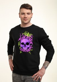 Schwarzes Sweatshirt mit einem großen lila Schädel-Design, umgeben von grünen und pinken Texten und Mustern. Der Stoff hat eine glatte Textur.