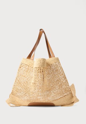 Borsa a tracolla beige intrecciata con design a trama aperta, ampie spalline in pelle marrone e base solida, posizionata su uno sfondo chiaro uniforme.