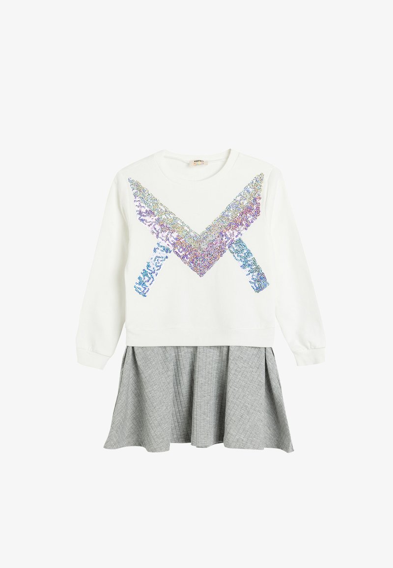 Sweatshirt blanc avec un design en sequins multicolores en chevrons, associé à une jupe grise plissée avec un motif texturé.