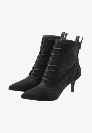 Botines negros hasta el tobillo con detalles de encaje, puntera afilada y un tacón bajo. Fabricados en ante y tela, cuentan con cordones decorativos y una lengüeta en la parte trasera.