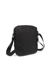 Borsa a tracolla nera in nylon con logo impresso, chiusura con zip, tracolla regolabile e texture liscia. Forma rettangolare compatta.