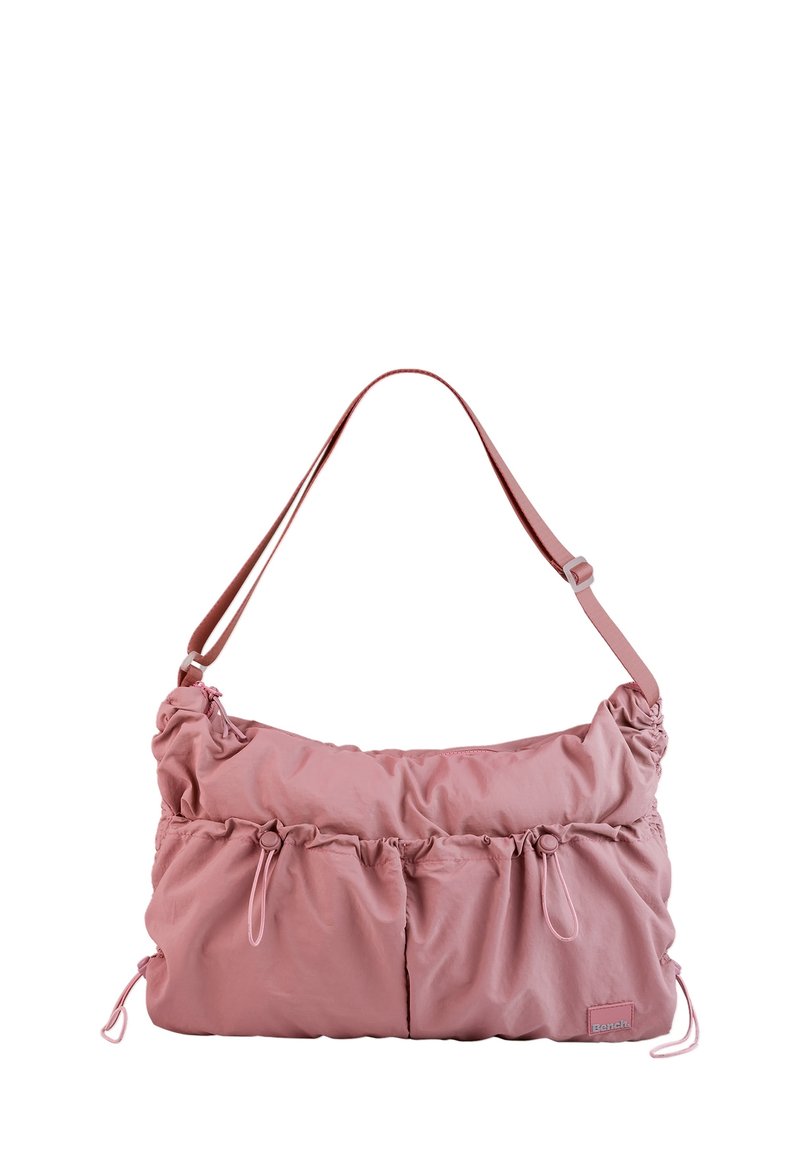 Sac à épaule en tissu rose avec texture plissée, deux poches avant, une bandoulière ajustable et des accents à cordon sur les côtés.