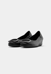 Black ballet flats with a rounded toe, made of smooth leather. Feature a prominent black buckle on the front and a low wedge heel.