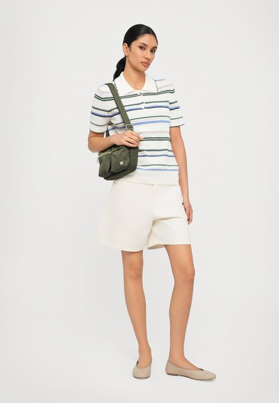 Polo a righe con colletto, pantaloni beige, e scarpe basse. Borsa a tracolla verde oliva, che evidenzia un look rilassato e informale.