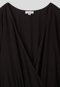 Abito nero avvolgente realizzato in tessuto leggero, con scollatura a V profonda e un design fluido con sottili dettagli di cucitura. Etichetta del marchio visibile.