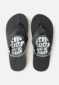 Black flip flops with textured soles and wide straps. The footbed features a white circular graphic with bold text and logo accents.