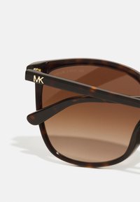 Brown gradient sunglasses with tortoiseshell frames, featuring a gold "MK" logo on the temple and a smooth, glossy finish.