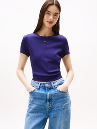 Tricou scurt cu mânecă, ribbed, de culoare violet, cu un design adaptat, având un logo mic pe piept. Asortat cu blugi din denim ușor, de un albastru deschis, cu talie înaltă.