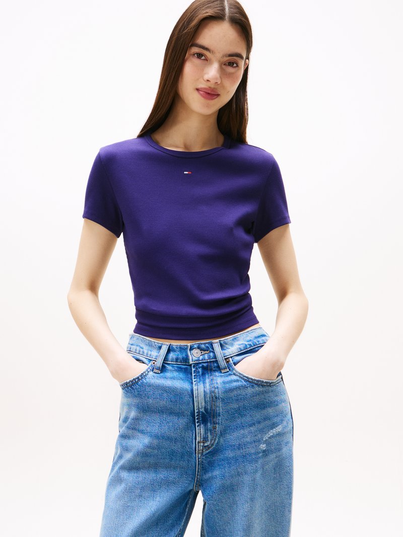 Tricou scurt cu mânecă, ribbed, de culoare violet, cu un design adaptat, având un logo mic pe piept. Asortat cu blugi din denim ușor, de un albastru deschis, cu talie înaltă.