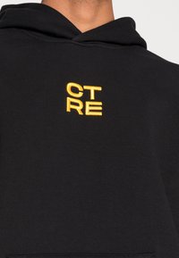 Felpa nera con cappuccio, dotata di coulisse, con testo ricamato giallo "CT RE" sul petto. Tessuto morbido e vestibilità standard.