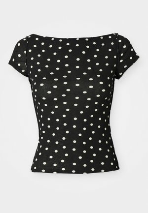 Črna majica s kratkimi rokavi, okrašena z belimi pikami. Ima čolnasti izrez in prilegajoče se pas, izdelana iz mehke, lahke tkanine.