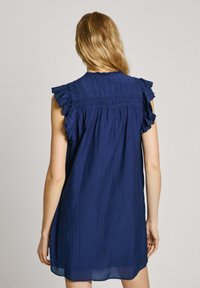 Marineblaues ärmelloses Kleid mit gerafften Schulterrüschen, schulterfreier Rückendekoration und lässigem Schnitt. Hergestellt aus einem leichten Stoff.