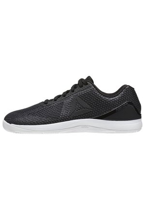 Baskets de sport en mesh noir avec semelle blanche, lacets et logo triangulaire sur le côté, vues de l'extérieur.
