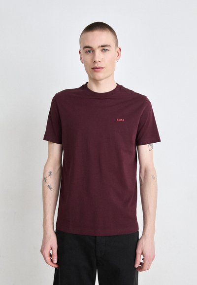 T-shirt bordeaux à manches courtes en coton. Présente un petit logo "BOSS" rouge sur la poitrine. Coupe droite et design col rond.