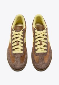 Sneaker in suede marrone con dettagli gialli, dotati di lacci piatti, tomaia testurizzata e suola in gomma con un leggero motivo di battistrada.