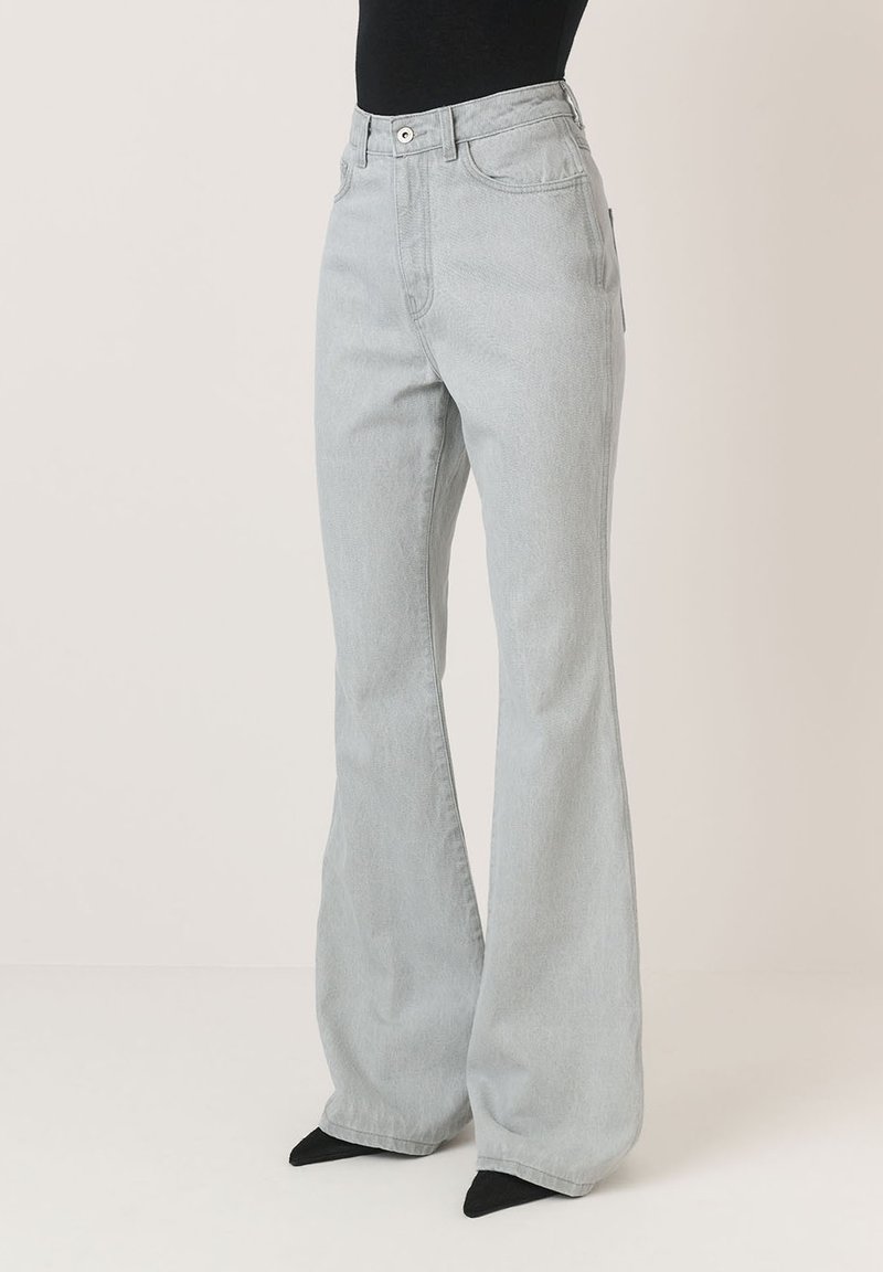 Šviesiai pilkos plačios džinsinės kelnės su aukštu liemeniu, užsegimu mygtuku ir užtrauktuku, bei penkių kišenių dizainu. Pagamintos iš lygaus džinsinio audinio.