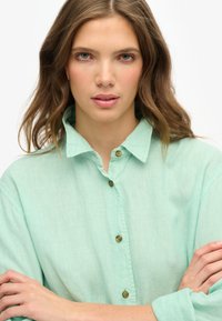Mintgroene button-up shirt met een kraag, gemaakt van lichte stof, met een relaxte pasvorm en zichtbare knoopaccenten.