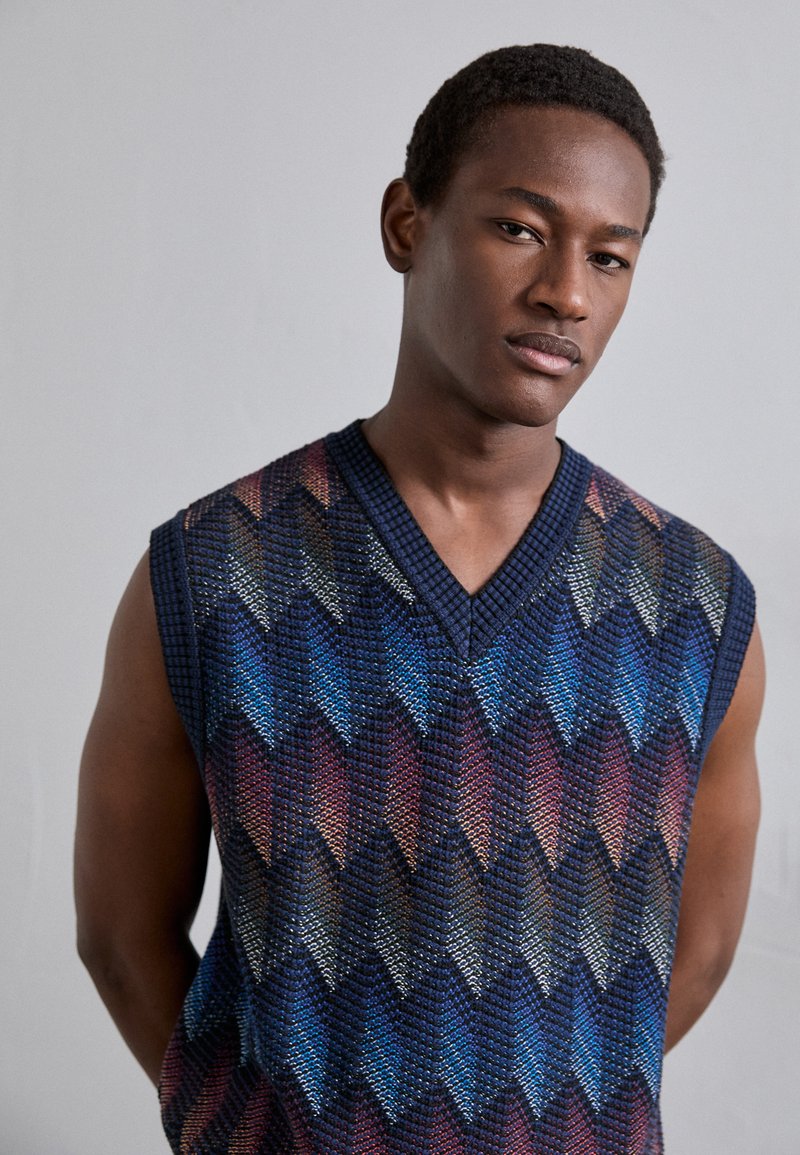 Gilet in maglia senza maniche con scollatura a V, motivo geometrico in tonalità di blu, rosso e nero, tessuto strutturato e costina a contrasto.