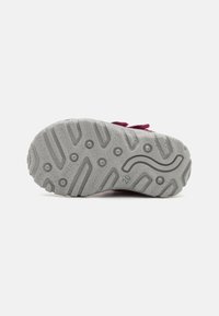 Suola di scarpa in gomma grigia con motivi testurizzati e grip circolari; presenta un delicato design a linee curve al centro e bordi rialzati.