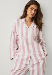 Pyjama rayé en mélange de lin rose pâle et blanc, composé d'une chemise à boutons avec col et manches longues, assortie d'un pantalon.