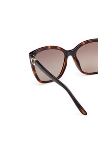 Ochelari de soare din material tartar cu o formă unică de ochi de pisică, lentile degradate și un accent de hardware auriu pe balama, având un tempel elegant de culoare neagră.
