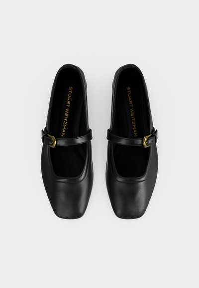 Paire de ballerines Mary Jane noires à bout carré avec brides à boucle dorée, vues de dessus sur fond blanc uni.