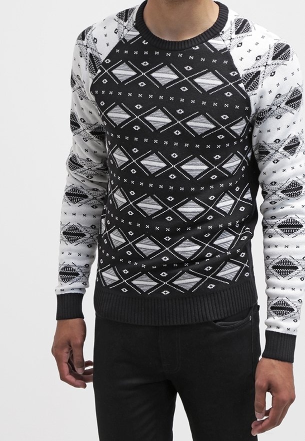 Pull à motifs noirs et blancs avec des designs géométriques, manches raglan, encolure et poignets côtelés, fabriqué en tissu tricoté.