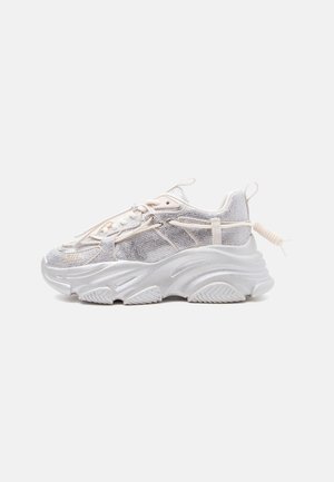 Χοντρό λευκό αθλητικό παπούτσι με πλέγμα πάνελ, παχύ ανάγλυφο σόλα, ελαστικά κορδόνια με θηλιά και θηλιά στο πίσω μέρος, εμφανίζεται σε πλαϊνή όψη.