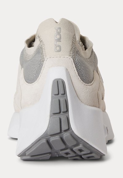 Baskets Polo beige et grises vues de dos, avec tissu texturé, détails en cuir suédé, et une semelle épaisse blanche et grise avec motif de crampons.