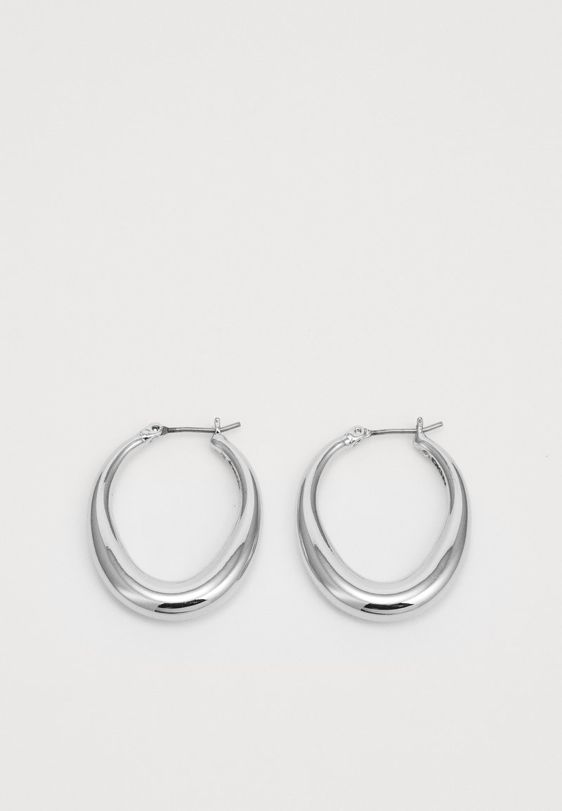 Une paire de boucles d'oreilles en croissant en argent poli avec des fermoirs à charnière sur un fond blanc.