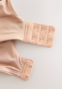 Fermeture dos de soutien-gorge beige avec trois rangées de crochets et deux colonnes d'œillets pour un ajustement réglable.