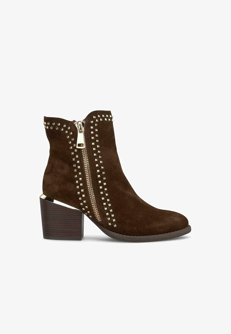 Botín de ante marrón hasta el tobillo con cremallera lateral, acentos de tachuelas metálicas y un tacón grueso texturizado con acabado parecido a la madera.