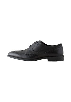 Schwarzer Herren-Brogue-Lederschuh mit perforierten Details und Schnürsenkeln, seitlich auf weißem Hintergrund gezeigt.