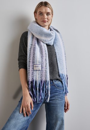 Foulard bleu clair avec des rayures violettes, bords frangés et finition texturée. L'étiquette attachée indique "COLORFUL" en marine. Porté sur un haut sombre.