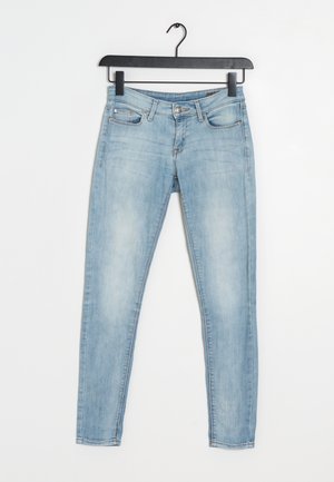 Jeans skinny de mezclilla azul claro con un diseño estándar de cinco bolsillos. La tela tiene una textura suave y ligeramente desgastada. Cuenta con un cierre de botón y cremallera.