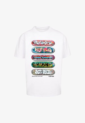 White t-shirt featuring five skateboard deck graphics with colorful graffiti designs and the text "FROM THE STREET FOR THE STREET" below.