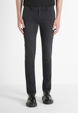 Dark denim jeans feature a slim fit design, visible stitching, five-pocket style, and are paired with black lace-up boots.